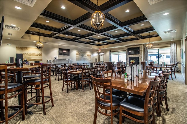 carpeted dining room featuring beam ceiling, coffered ceiling, a large fireplace, and an inviting chandelier