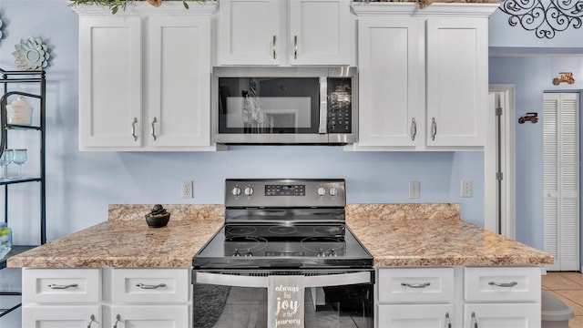 kitchen with light stone countertops, tile patterned floors, white cabinets, and stainless steel appliances