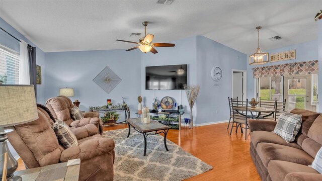 living room with ceiling fan, light hardwood / wood-style floors, lofted ceiling, and plenty of natural light