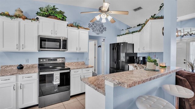 kitchen featuring a breakfast bar area, white cabinetry, and appliances with stainless steel finishes