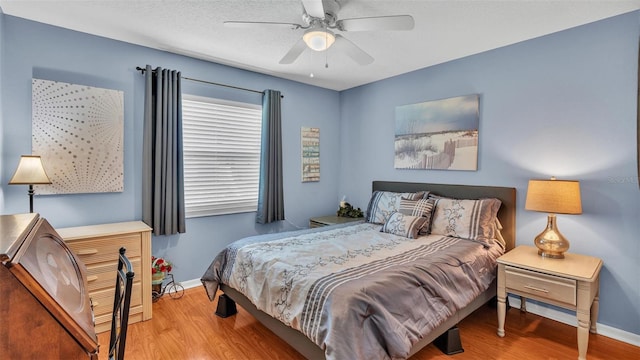 bedroom featuring light wood-type flooring, a textured ceiling, and ceiling fan