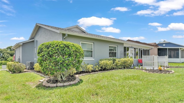 view of property exterior featuring central air condition unit, a yard, and a sunroom