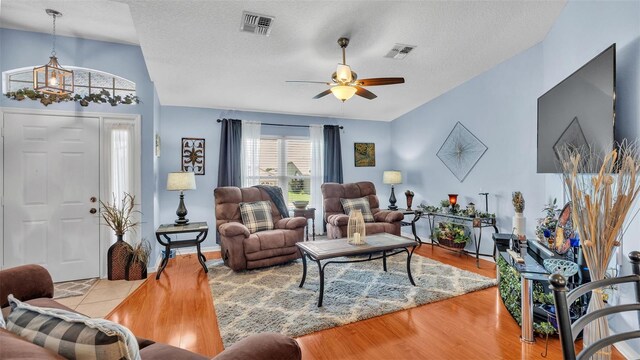 living room with ceiling fan, light hardwood / wood-style flooring, and a textured ceiling