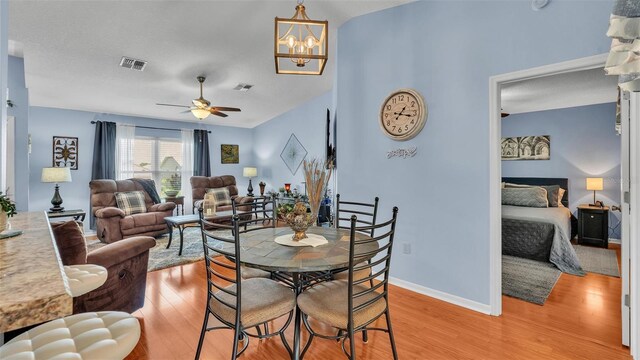 dining room featuring ceiling fan with notable chandelier and light hardwood / wood-style flooring