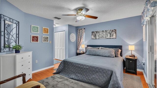 bedroom featuring ceiling fan, a textured ceiling, a closet, and light hardwood / wood-style flooring