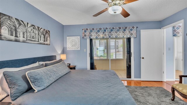 bedroom with ceiling fan, light hardwood / wood-style floors, a textured ceiling, and connected bathroom