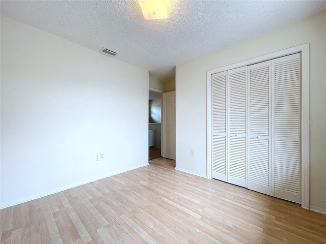 unfurnished bedroom featuring light wood-type flooring, a textured ceiling, and a closet