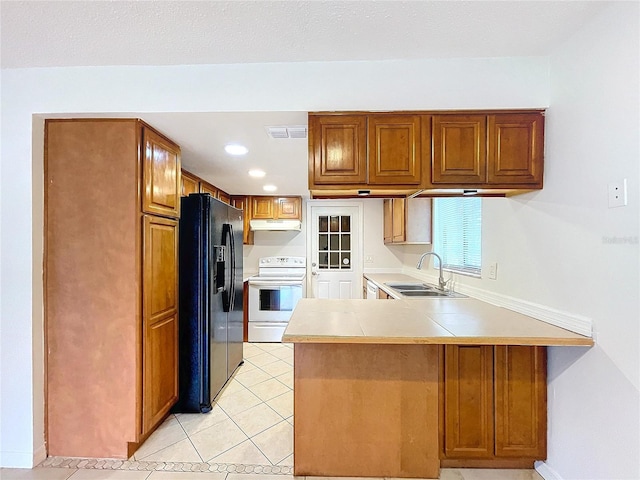 kitchen with sink, light tile patterned floors, kitchen peninsula, black fridge, and electric stove