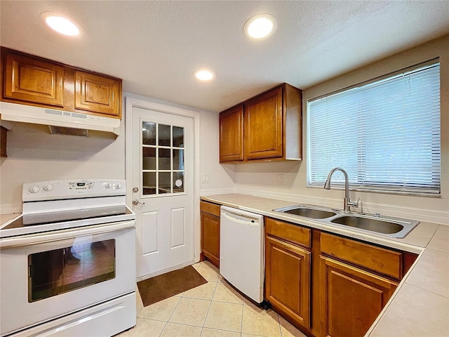 kitchen with sink, white appliances, light tile patterned floors, and a textured ceiling