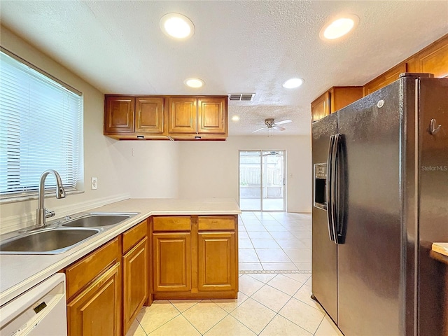 kitchen with dishwasher, sink, light tile patterned floors, black fridge with ice dispenser, and a textured ceiling