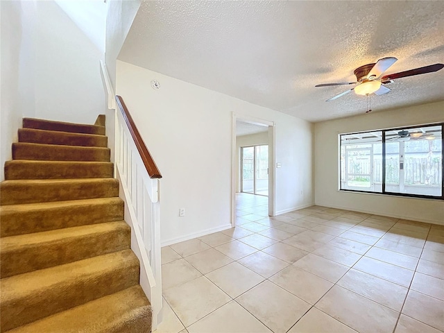 staircase with tile patterned flooring, a textured ceiling, and ceiling fan