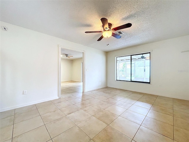 spare room featuring ceiling fan, a textured ceiling, and light tile patterned floors