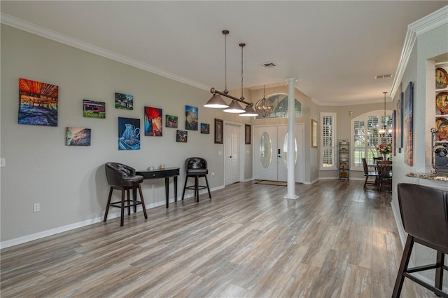 interior space with decorative columns, crown molding, wood-type flooring, and a chandelier