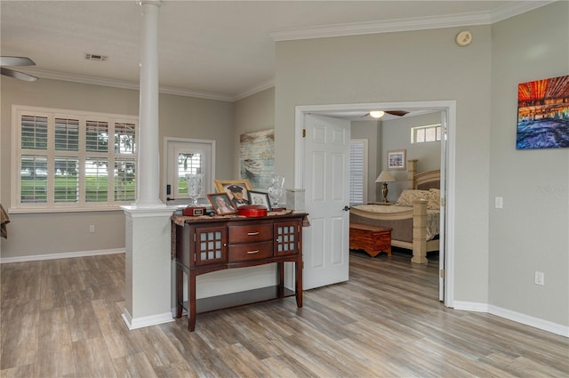 hall featuring ornate columns, crown molding, and light hardwood / wood-style floors