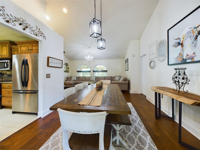 dining area featuring vaulted ceiling, dark hardwood / wood-style flooring, and a chandelier