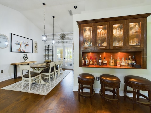 bar with dark brown cabinetry, dark wood-type flooring, decorative light fixtures, and lofted ceiling