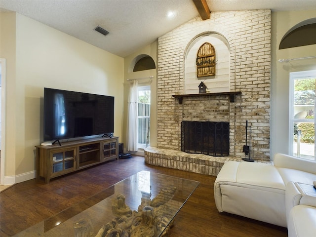 living room with a wealth of natural light, a fireplace, brick wall, and lofted ceiling with beams