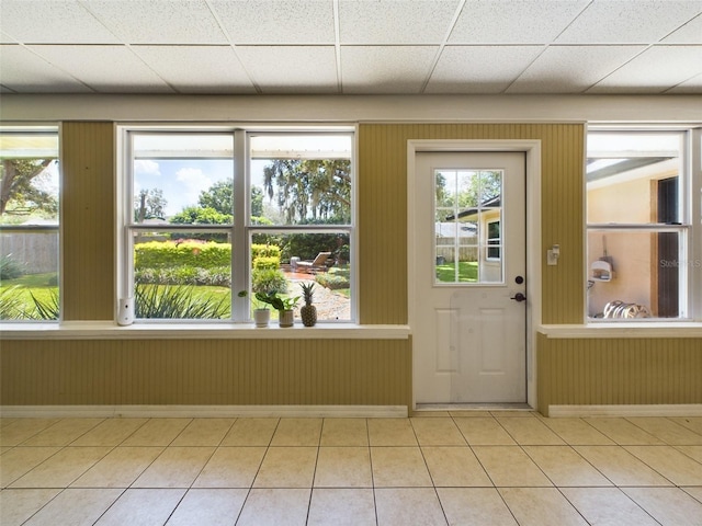 doorway with light tile patterned floors and a drop ceiling