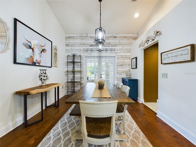 dining room featuring wooden walls, dark wood-type flooring, french doors, and lofted ceiling