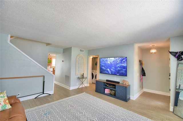 living room featuring a textured ceiling, wood-type flooring, and washing machine and clothes dryer