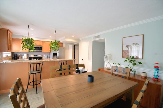 dining space featuring ornamental molding and light wood-type flooring