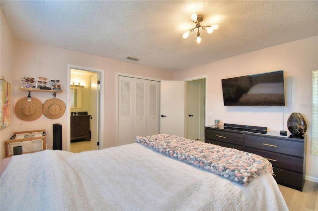 bedroom with ensuite bath, light hardwood / wood-style flooring, a closet, and a textured ceiling