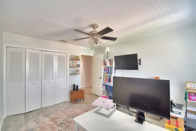 office area with a textured ceiling, ceiling fan, and light hardwood / wood-style flooring