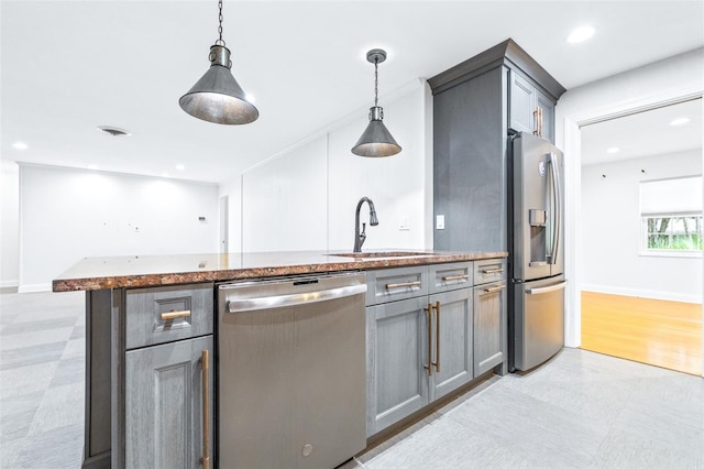 kitchen featuring sink, a center island with sink, gray cabinets, pendant lighting, and stainless steel appliances