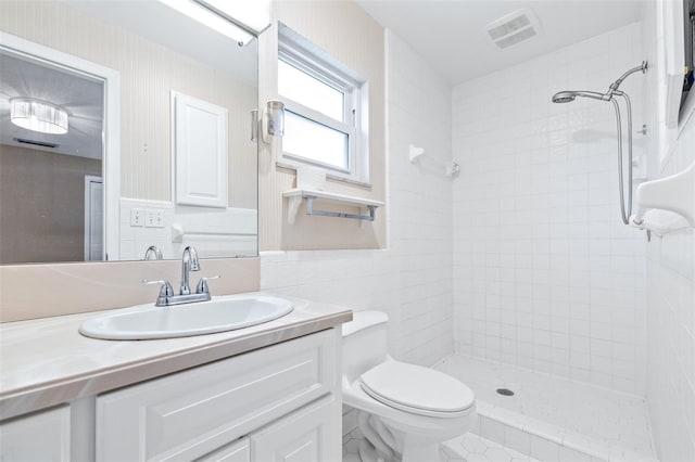 bathroom featuring vanity, tile walls, toilet, and tiled shower