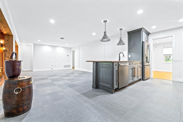 kitchen featuring stainless steel appliances, decorative light fixtures, sink, and dark colored carpet