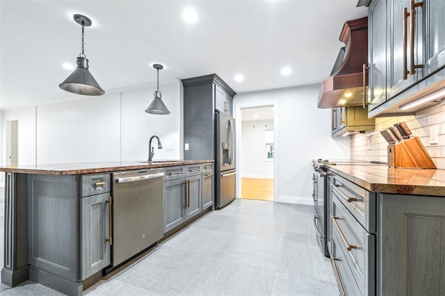 kitchen with wall chimney exhaust hood, sink, decorative light fixtures, appliances with stainless steel finishes, and gray cabinets