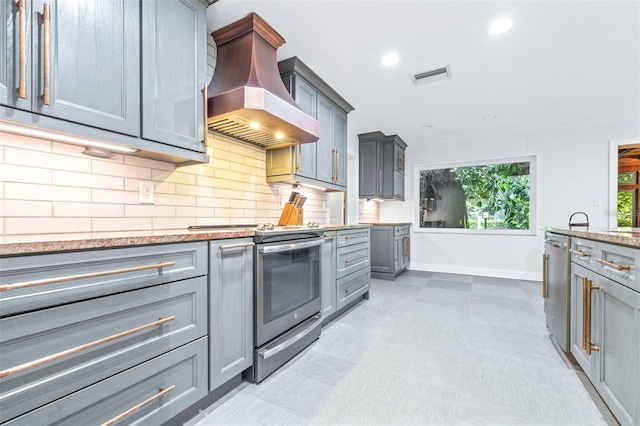 kitchen with appliances with stainless steel finishes, extractor fan, decorative backsplash, and gray cabinetry