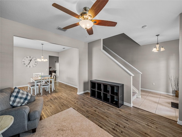 living room featuring wood-type flooring and ceiling fan with notable chandelier