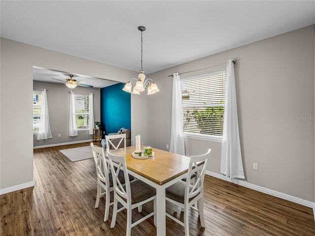 dining space featuring ceiling fan with notable chandelier and dark hardwood / wood-style flooring