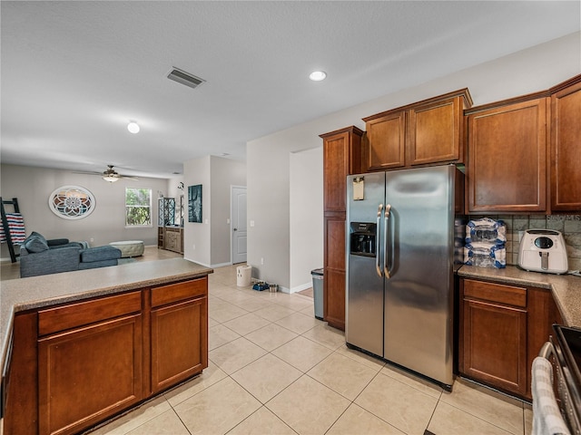 kitchen with range, light tile patterned floors, backsplash, ceiling fan, and stainless steel refrigerator with ice dispenser