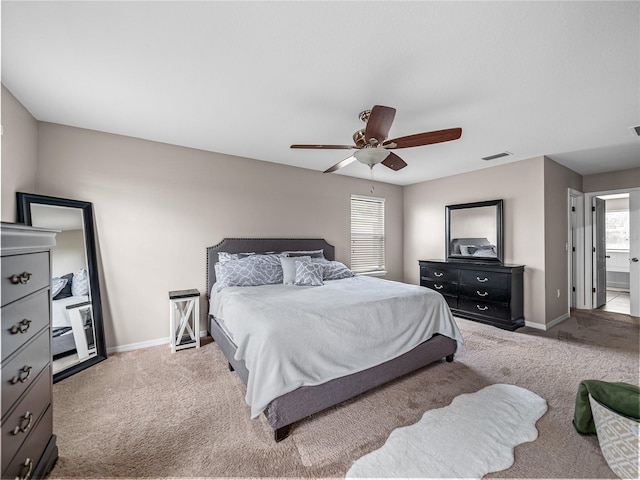 carpeted bedroom with ensuite bathroom and ceiling fan