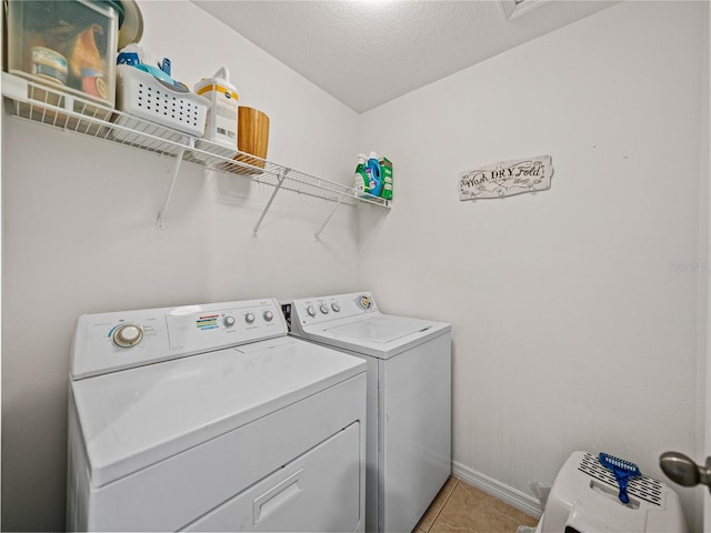 washroom with light tile patterned flooring, separate washer and dryer, and a textured ceiling