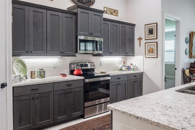 kitchen featuring appliances with stainless steel finishes, light stone countertops, and backsplash