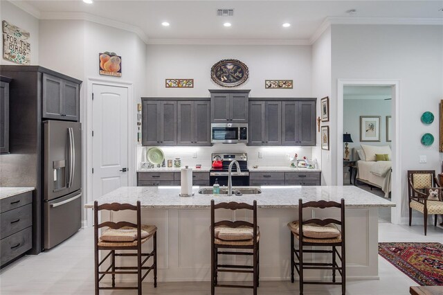 kitchen featuring a breakfast bar, appliances with stainless steel finishes, sink, and a kitchen island with sink