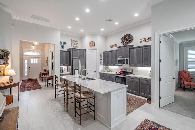 kitchen featuring sink, a breakfast bar area, stainless steel appliances, light stone countertops, and a kitchen island with sink