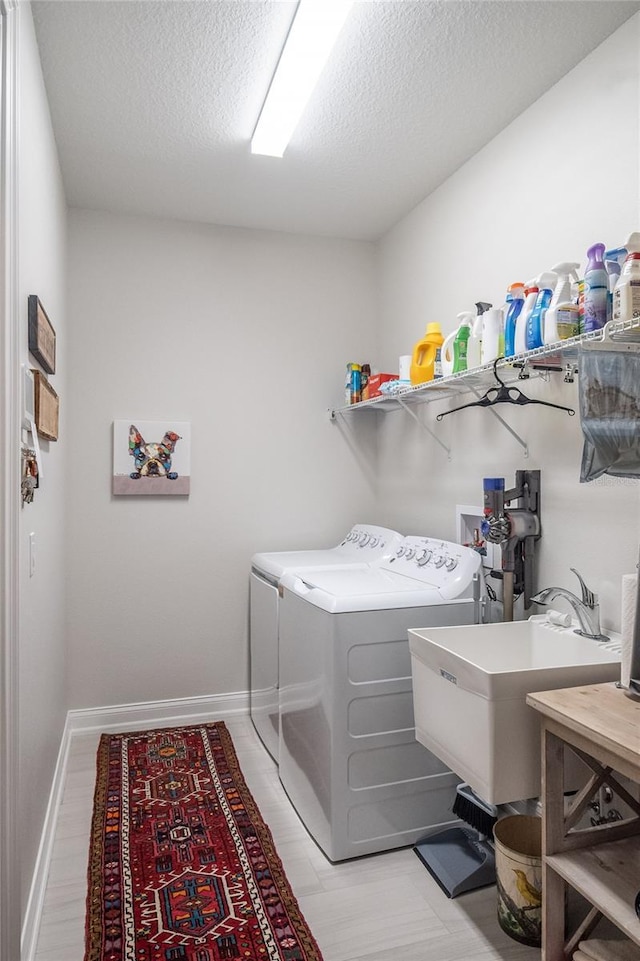 laundry room featuring sink, a textured ceiling, and washing machine and clothes dryer