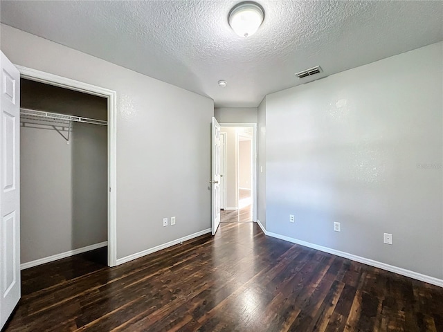 unfurnished bedroom featuring a textured ceiling, a closet, and wood-type flooring