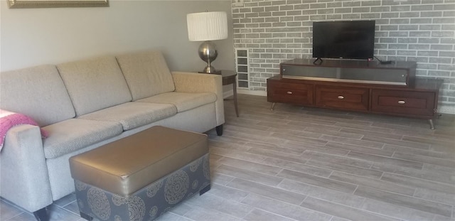 living room with brick wall and wood-type flooring