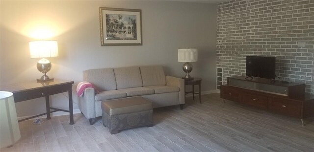 living room featuring hardwood / wood-style flooring and brick wall