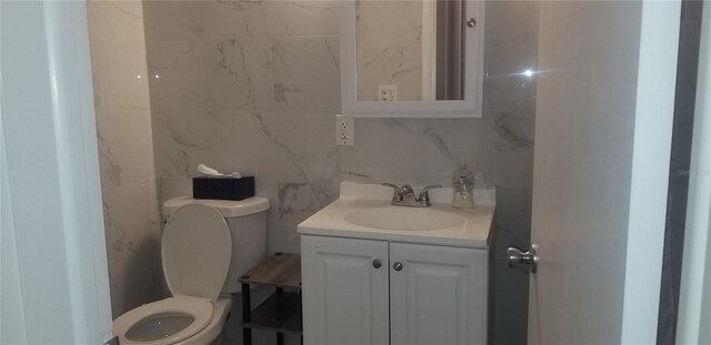 bathroom featuring vanity, toilet, and tile walls