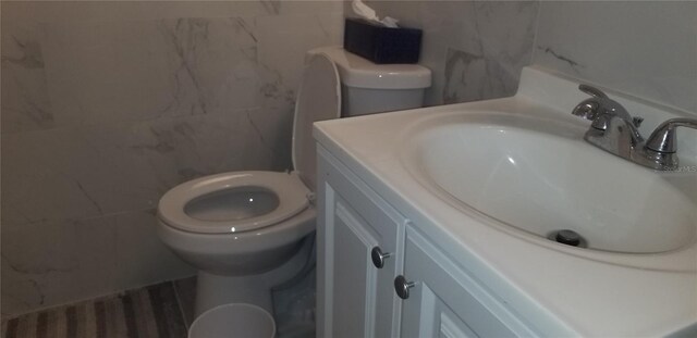 bathroom featuring hardwood / wood-style flooring, tile walls, toilet, and vanity