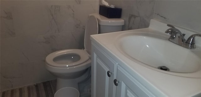 bathroom with vanity, tile walls, and toilet