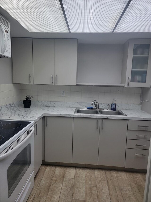 kitchen featuring light stone counters, sink, white appliances, and gray cabinets