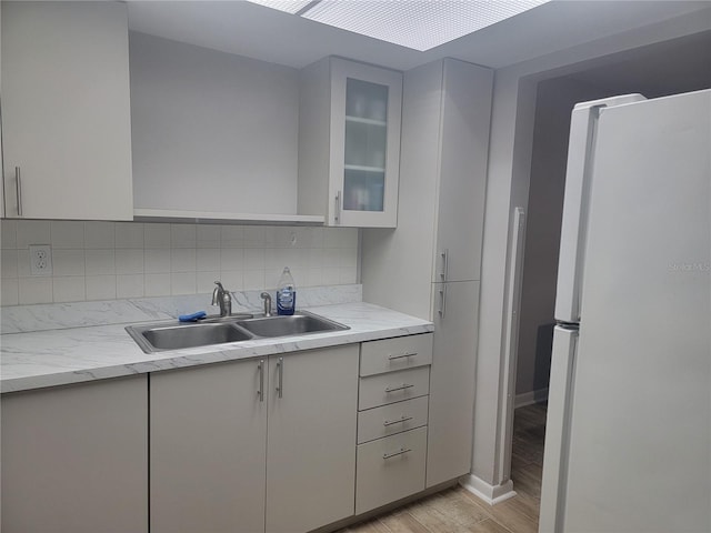 kitchen with decorative backsplash, sink, white refrigerator, and light hardwood / wood-style floors