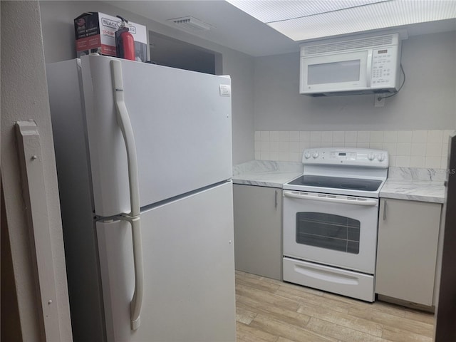 kitchen featuring gray cabinets, white appliances, and light hardwood / wood-style floors